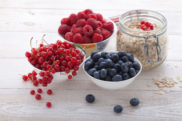 Breakfast - berries, fruit and muesli on white wooden