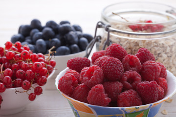 Breakfast - berries, fruit and muesli on white wooden