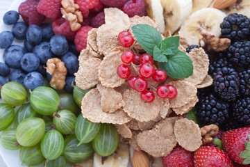Breakfast - berries, fruit and muesli on white wooden