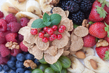Breakfast - berries, fruit and muesli on white wooden