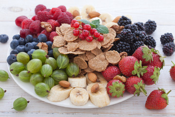 Breakfast - berries, fruit and muesli on white wooden