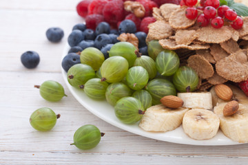 Breakfast - berries, fruit and muesli on white wooden