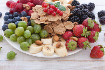 Breakfast - berries, fruit and muesli on white wooden