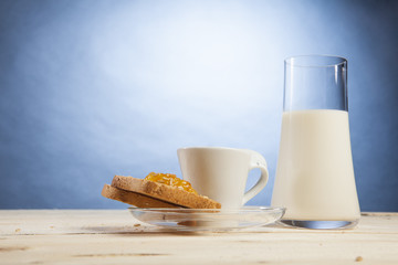 Bicchiere di latte con tazzina di caffè e fetta biscottata con marmellata a forma di cuore