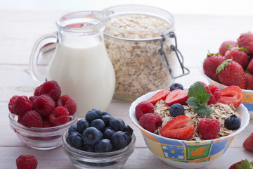 Breakfast - berries, fruit and muesli on white wooden