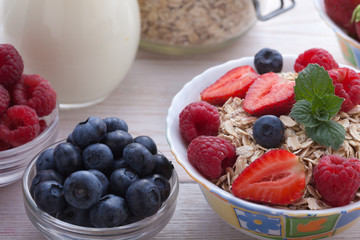 Breakfast - berries, fruit and muesli on white wooden