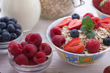 Breakfast - berries, fruit and muesli on white wooden