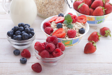 Breakfast - berries, fruit and muesli on white wooden