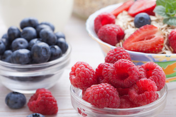 Breakfast - berries, fruit and muesli on white wooden
