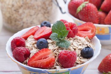 Breakfast - berries, fruit and muesli on white wooden