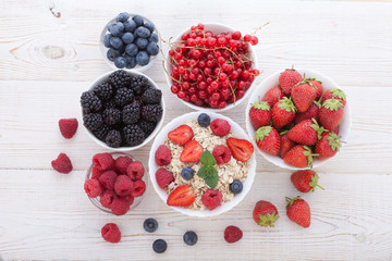 Breakfast - berries, fruit and muesli on white wooden