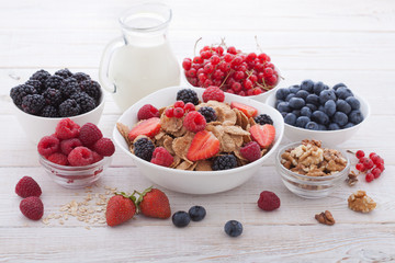 Breakfast - berries, fruit and muesli on white wooden