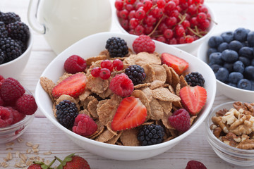 Breakfast - berries, fruit and muesli on white wooden