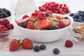 Breakfast - berries, fruit and muesli on white wooden