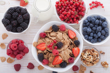 Breakfast - berries, fruit and muesli on white wooden