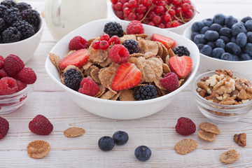 Breakfast - berries, fruit and muesli on white wooden