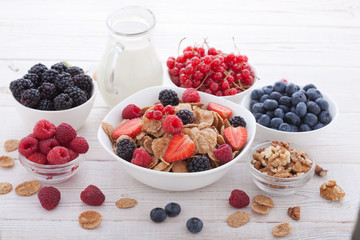 Breakfast - berries, fruit and muesli on white wooden