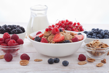 Breakfast - berries, fruit and muesli on white wooden