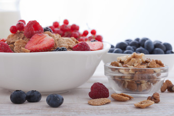 Breakfast - berries, fruit and muesli on white wooden