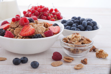 Breakfast - berries, fruit and muesli on white wooden