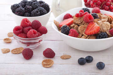 Breakfast - berries, fruit and muesli on white wooden