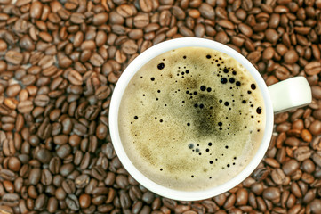 Coffee bean background with cup of fresh hot coffee close up