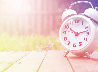 Classic alarm clock on wood against nature background