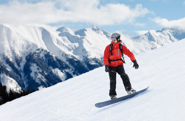 Snowboarder in red jacket sliding down the slope