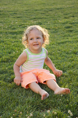 Adorable child sittng barefoot on the grass