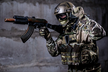 Armed ranger in camouflage,mask and helmet shows special signal