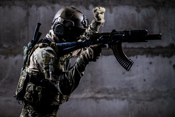 Armed soldier in camouflage with weapon shows special signal