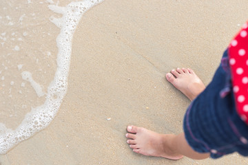 Legs of children stand on the beach