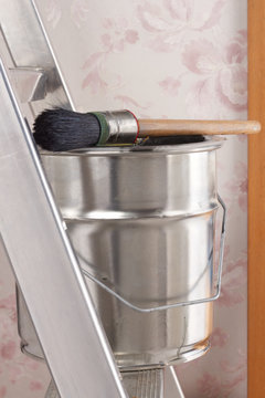 Bucket of paint and brush on stepladder