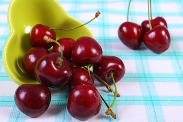 Fresh cherries in green bowl on checkered tablecloth, healthy food
