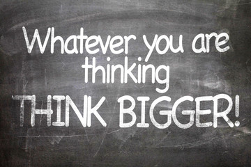 Fototapeta premium Whatever You Are Thinking Think Bigger written on a chalkboard