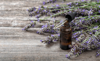 Herbal oil and lavender flowers bouquet on wooden background