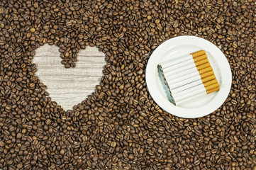 Coffee bean background with heart and many cigars on white plate
