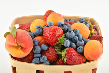 Fototapeta na wymiar Strawberries, apricots, blueberries, peach in basket isolated on