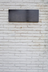 empty black sign made from marble board on white brick wall
