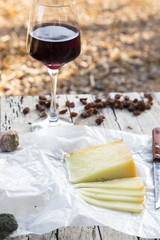 Pieces of cheese and raisins with a red wine glass on a old wood table