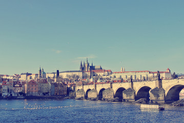 Fototapeta na wymiar Charles' Bridge with Hradcany castle in the background in Prague, Czech Republic, on a sunny day. Image filtered in faded, washed out, retro style; nostalgic travel vintage concept.