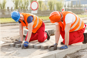 Construction workers putting paving stones
