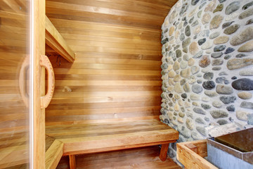 Perfect sauna room with wood walls and bench.