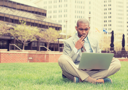 business man sitting outside corporate office working on compute
