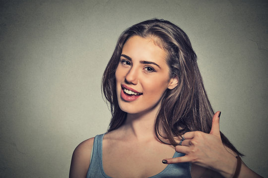 Young Woman Making A Call Me Sign And Smiling