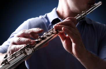 Flutist in a blue shirt on dark background © Zerophoto