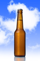 golden beer with frost bubbles in brown glass bottle isolated on blue sky