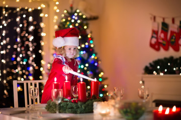 Fototapeta na wymiar Little girl lighting candles at Christmas dinner