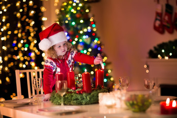 Fototapeta na wymiar Little girl lighting candles at Christmas dinner