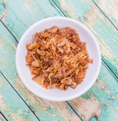 Deep fried shallots for garnishing in white bowl over wooden background